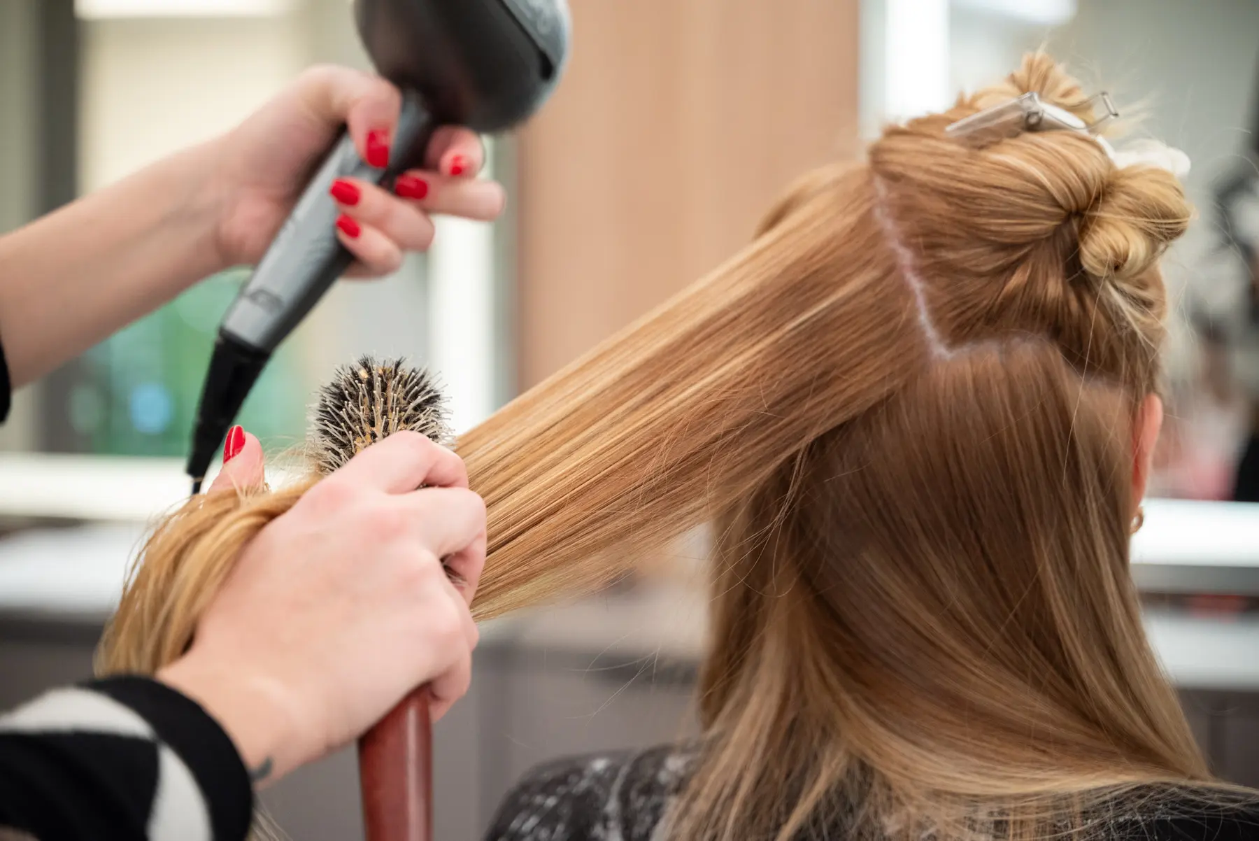Escova e finalização de cabelo loiro com escova redonda e secador em salão de Curitiba